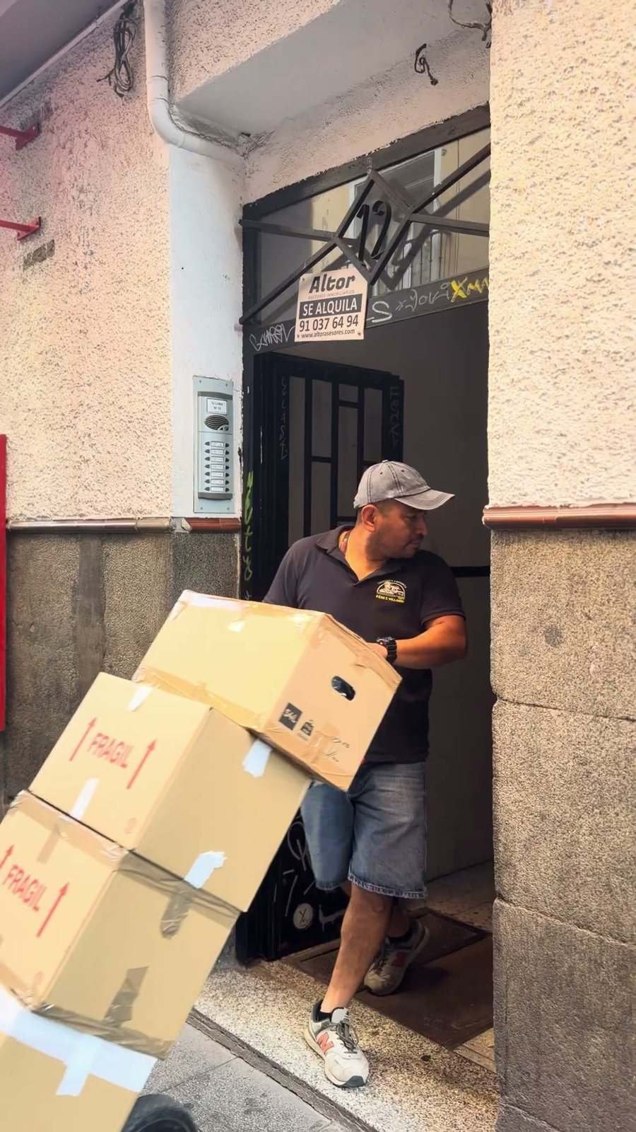 A mover wheels cardboard boxes out through a building doorway